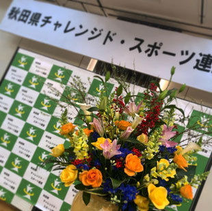 設立総会会場の花飾りとチャレンジドスポーツ連盟の看板